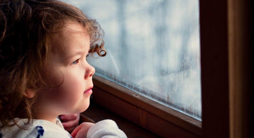 A young girl looks out a window.