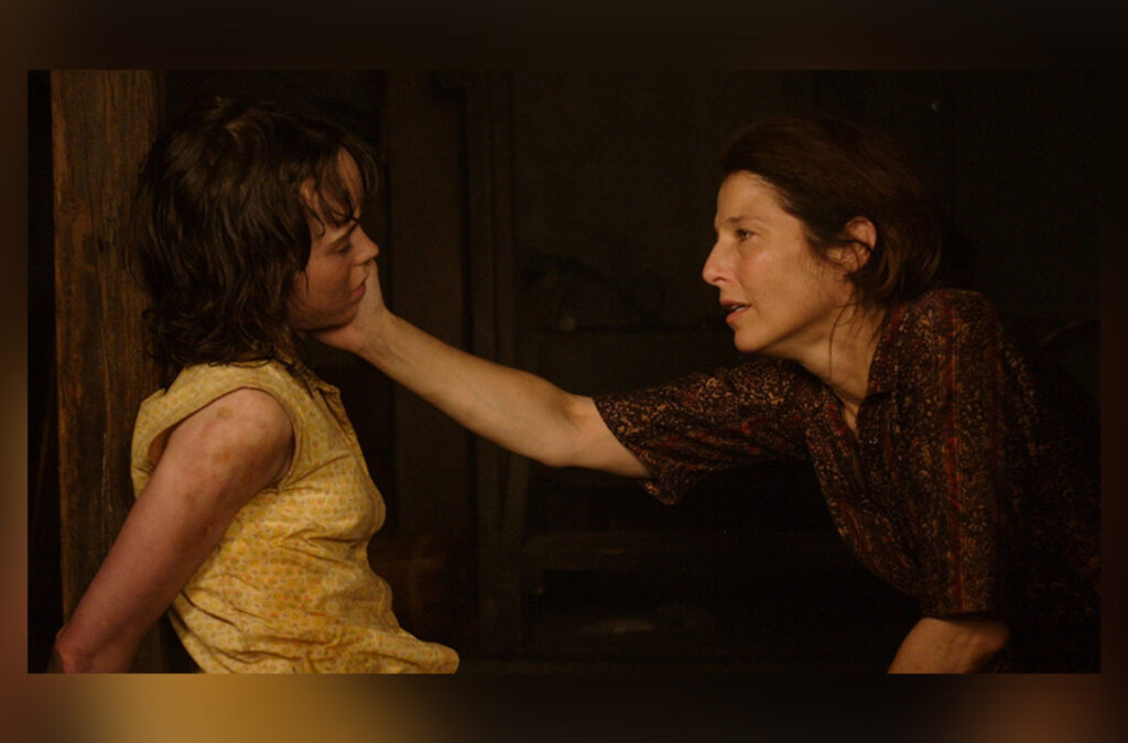 An American Crime scene from the movie showing Likens, tied up, as her guardian attempts to console her during a punishment.